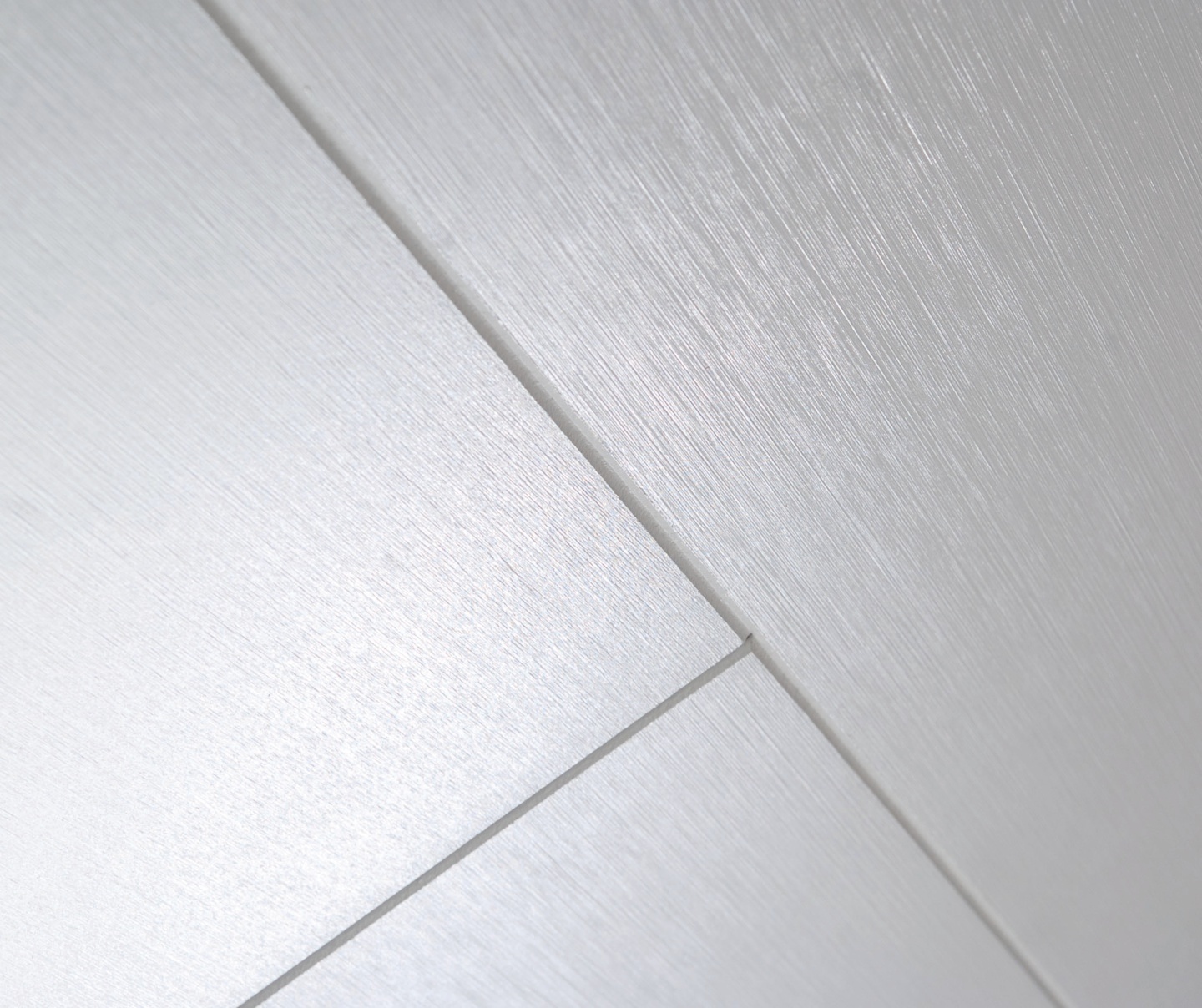 Ytan av två diagonala, släta plåtar med en borstad metallfinish. Nyansen är ljus och reflekterar ljus på ett subtilt sätt.